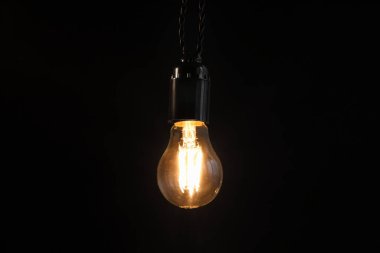 Koyu arkaplanda asılı parlayan ampul