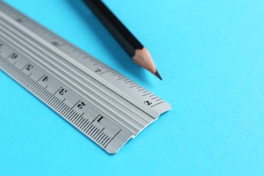 Açık mavi arkaplanda cetvel ve kalem, yakın plan