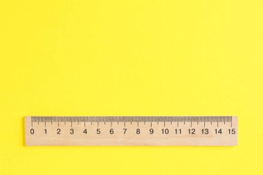 Sarı arka planda ahşap bir cetvel, üst manzara. Metin için boşluk