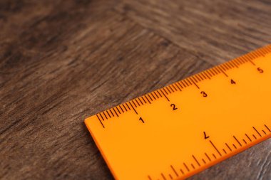 Bir turuncu cetvel ahşap masada, yakın plan.