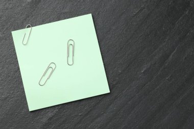 Kağıt not ve ataçlar siyah masanın üstünde, en üstte. Metin için boşluk