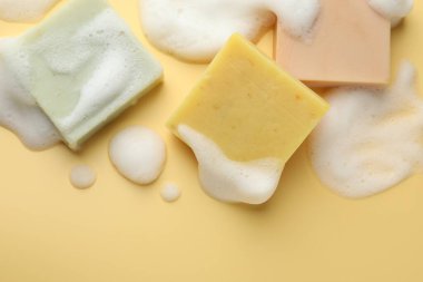 Sarı arka planda köpüklü sabun çubukları, düz yatış