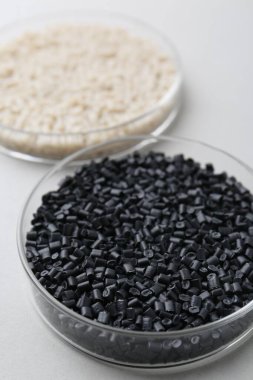 Gri arka planda petri kabında renkli plastik granüller, yakın plan.
