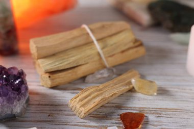 Palo Santo sopaları ve değerli taşlar beyaz ahşap masada, yakın plan.