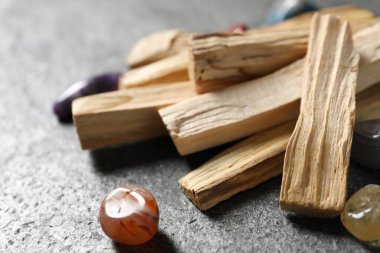 Palo santo sopaları ve değerli taşlar gri masada, yakın plan.