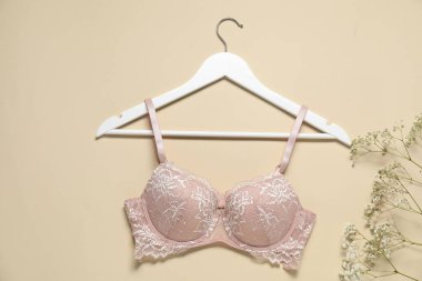 Güzel dantel sutyenli askı ve bej arka planda çiçekler, düz uzanmış