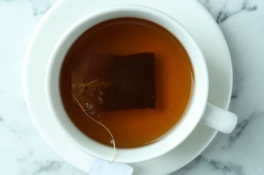 Bardakta çay poşeti, sıcak içecek açık mermer masa, üst manzara.