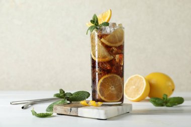 Limon dilimli taze buzlu kola ve beyaz ahşap masada nane şekeri.