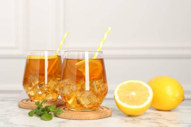 Buzlu çayı limon dilimleri, nane şekeri ve beyaz mermer masada pipet içerek tazeliyorum.