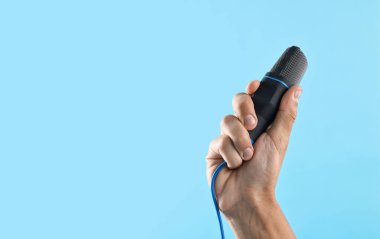 Açık mavi arka planda mikrofonu olan adam, yakın plan. Metin için boşluk