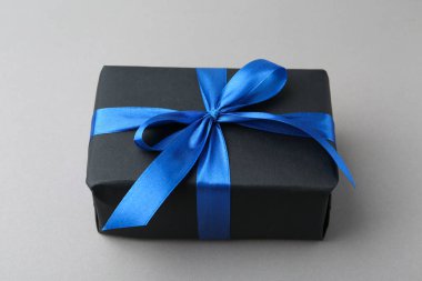 Gri arka planda mavi fiyonklu hediye kutusu, yakın plan.