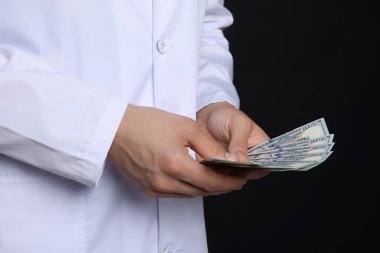 Yozlaşma konsepti. Siyah arka planda dolar banknotları olan doktor, yakın plan.