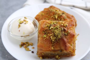 Lezzetli baklava, doğranmış fındık ve bir kepçe dondurma, yakın plan.