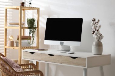 Merkez ofis. Beyaz duvarın yanında rahat bir iş yeri. Bilgisayarı ve diğer mobilyaları olan bir masa.