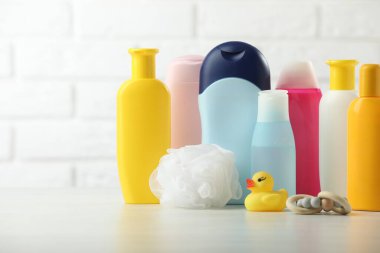 Bebek kozmetik ürünleri, duşlu puf, çıngırak ve beyaz tuğla duvara dayalı plastik ördek. Metin için boşluk
