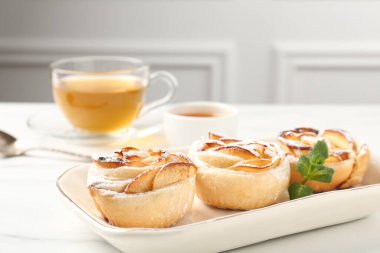 Nane, bal ve çay ile taze pişmiş elma gülleri beyaz mermer masada, yakın plan.