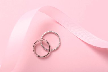Alyans ve kurdele pembe arka planda, üst manzara