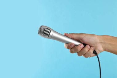 Açık mavi arka planda mikrofonu olan adam, yakın plan.