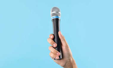 Açık mavi arka planda mikrofonu olan adam, yakın plan.