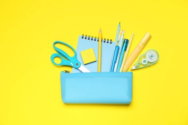 Kalem kutusu ve sarı zemin üzerinde farklı kırtasiye malzemesi, düz yatıyordu
