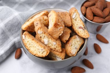 Lezzetli bademli bisküviler (Cantuccini) kasede ve fındıklar ışık masasında, yakın plan