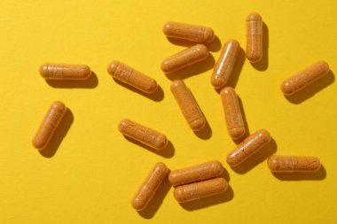 Sarı zemin üzerinde birçok zerdeçal kapsülü, düz yatıyordu