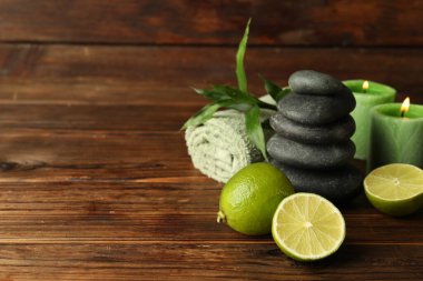 Taze limonlu spa kompozisyonu, çakıl taşları ve ahşap masada yanan mumlar, yakın çekim. Metin için boşluk