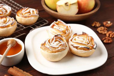 Ahşap masada servis edilen pudra şekerli elma gülleri, yakın plan.