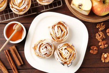 Ahşap masada servis edilen pudra şekerli lezzetli elma gülleri.