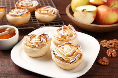 Ahşap masada servis edilen pudra şekerli elma gülleri, yakın plan.