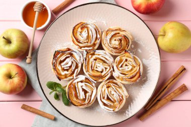 Pembe ahşap masada servis edilen pudra şekerli elma gülleri.