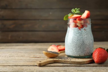 Çilekli lezzetli chia pudingi ve tahta masada cam kavanozda nane şekeri.