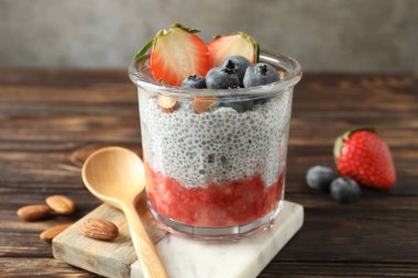 Çilekli Chia pudingi, yaban mersini ve bademler ahşap masada, yakın plan.