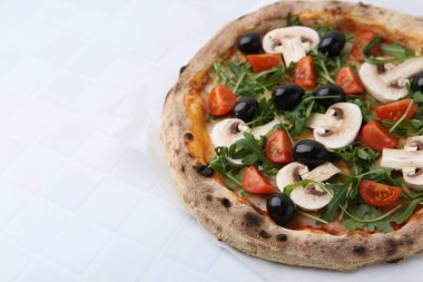 Kiraz domatesli lezzetli pizza, siyah zeytin, mantar ve roka, beyaz fayanslı masa, yakın çekim. Metin için boşluk