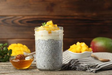 Bardakta mangolu lezzetli chia pudingi ve ahşap masada bal.