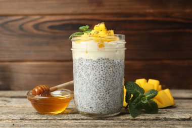 Bardakta mangolu lezzetli chia pudingi, ahşap masada nane ve bal.