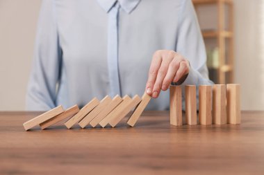 Masada tahta blokların düşmesini engelleyen kadın, yakın plan. Domino etkisi