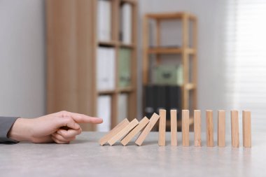 Domino etkisi. Masada tahta blokları iten kadın, yakın plan.
