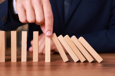 Ahşap blokların masada düşmesini engelleyen adam, yakın plan. Domino etkisi