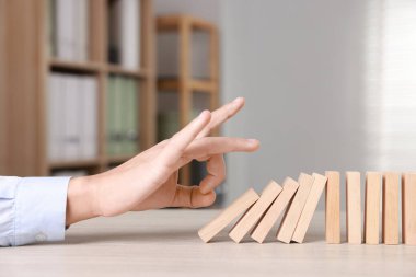 Domino etkisi. Masada tahta blokları iten adam, yakın plan.