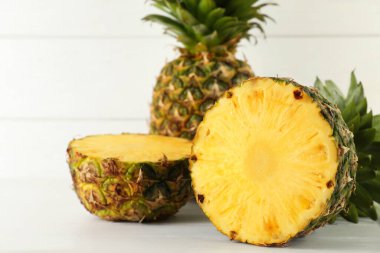 Tam ve dilimlenmiş taze ananas beyaz ahşap masada.