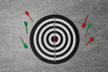 Dart tahtası ve gri mermer zemin üzerinde renkli oklar, düz konum