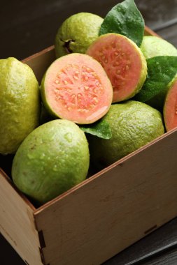 Taze kesilmiş ve tüm guava meyveleri siyah masanın üzerinde ahşap sandıkta, yakın plan.