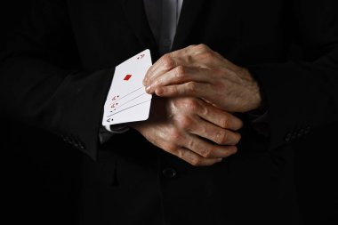 Illusionist taking playing cards out of sleeve on black background, closeup clipart