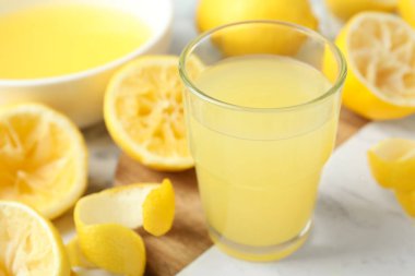 Bir bardak taze limon suyu ve sıkılmış meyveler, yakın plan.