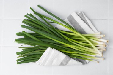 Beyaz fayanslı masada taze yeşil soğanlar, üst manzara.