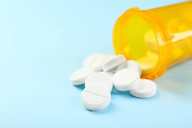 Açık mavi arka planda bir şişe antibiyotik hapı, yakın plan. Metin için boşluk