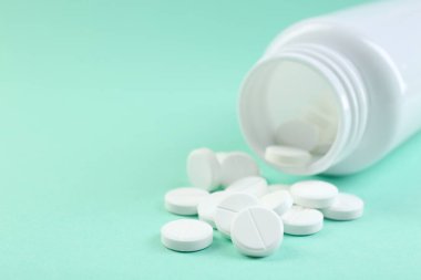 Turkuaz arka planda bir şişe antibiyotik hapı, yakın plan. Metin için boşluk