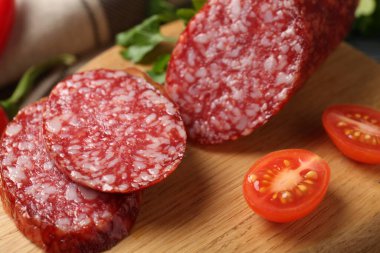 Ahşap tahtada füme sosis ve domates kes, yakın plan.