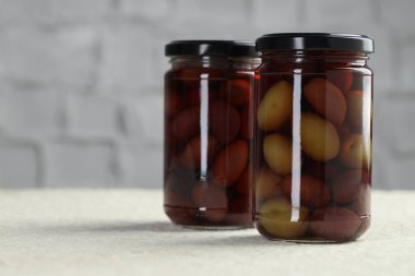 Kavanozlarda turşulu yeşil zeytin beyaz desenli masa, yakın çekim.